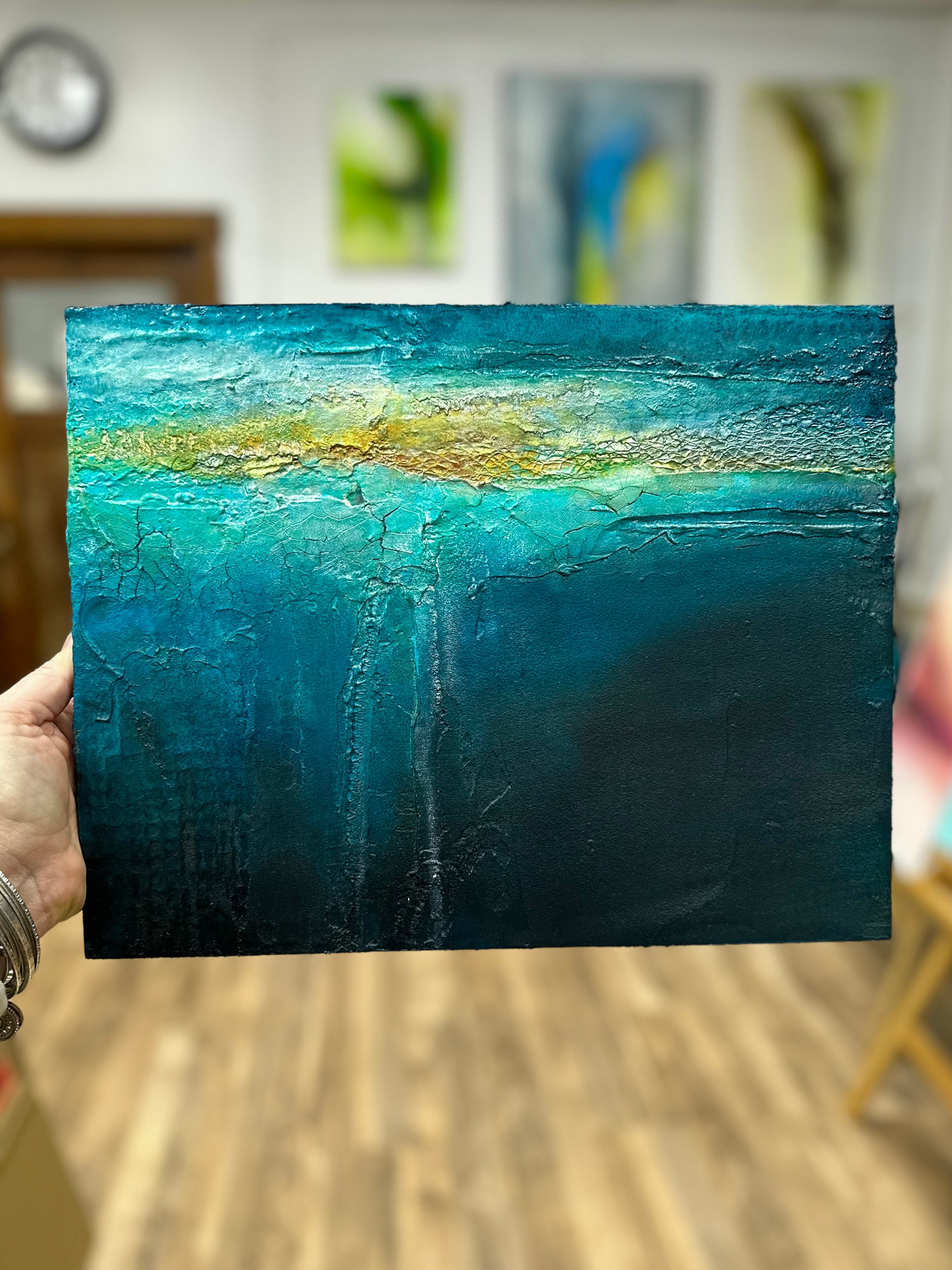 Abstract painting Beneath with blue and gold hues held by the artist