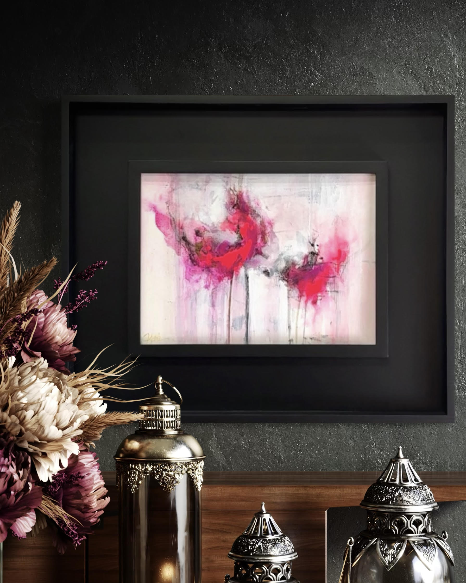 Framed, abstract, pink painting, on a dark wall with decorative elements below.